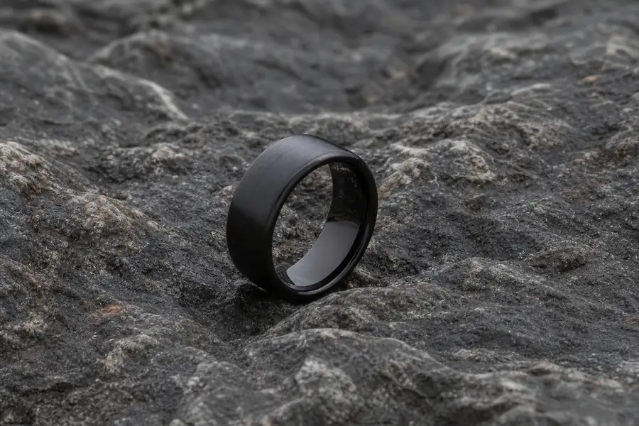 A matte black tungsten band on dark stone