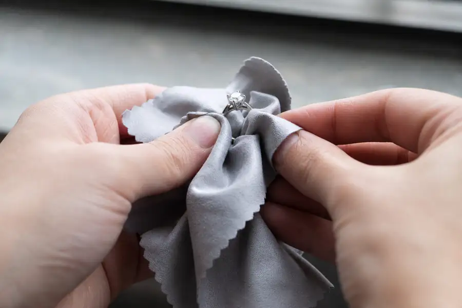Hands drying a ring with a microfibre cloth