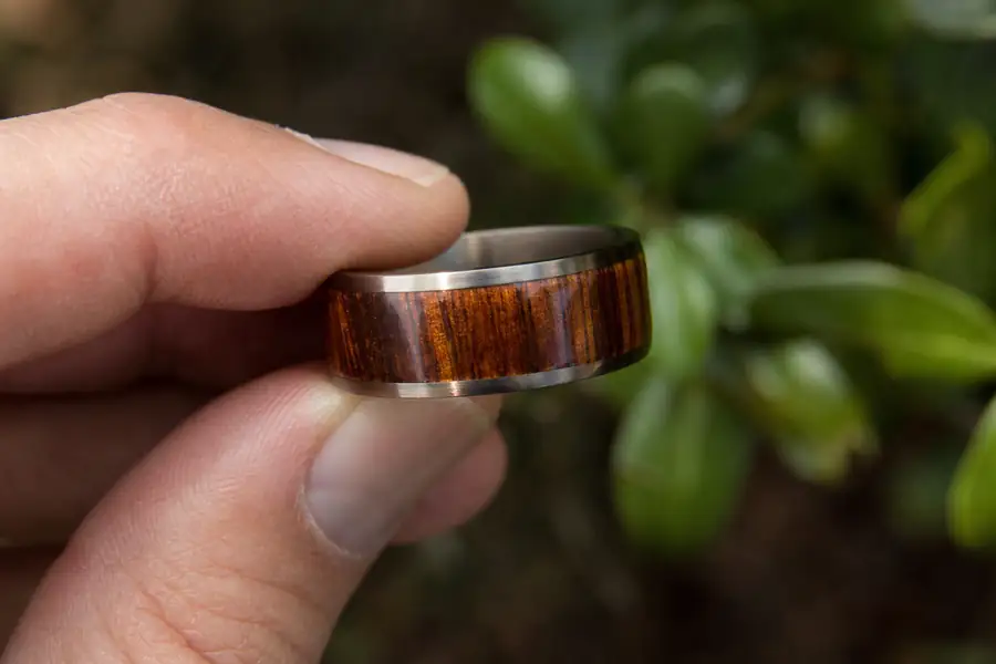 A koa inlay band held up to warm afternoon light