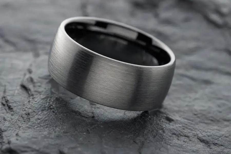 Macro shot of a brushed tungsten carbide band on dark slate