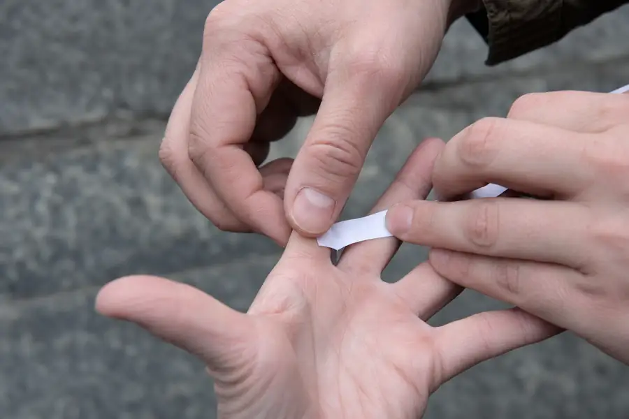 Hands measuring a finger with a paper strip