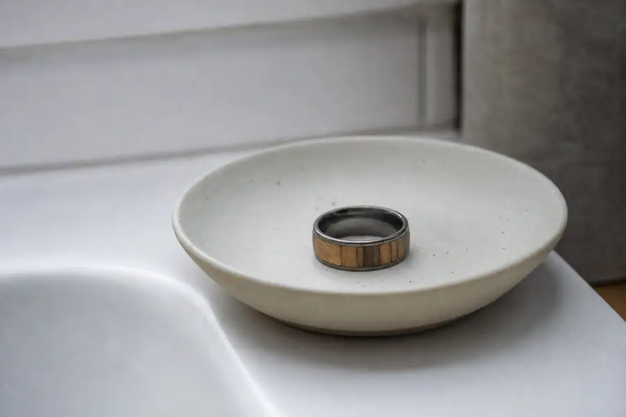 A wood inlay ring resting on a dish beside a sink